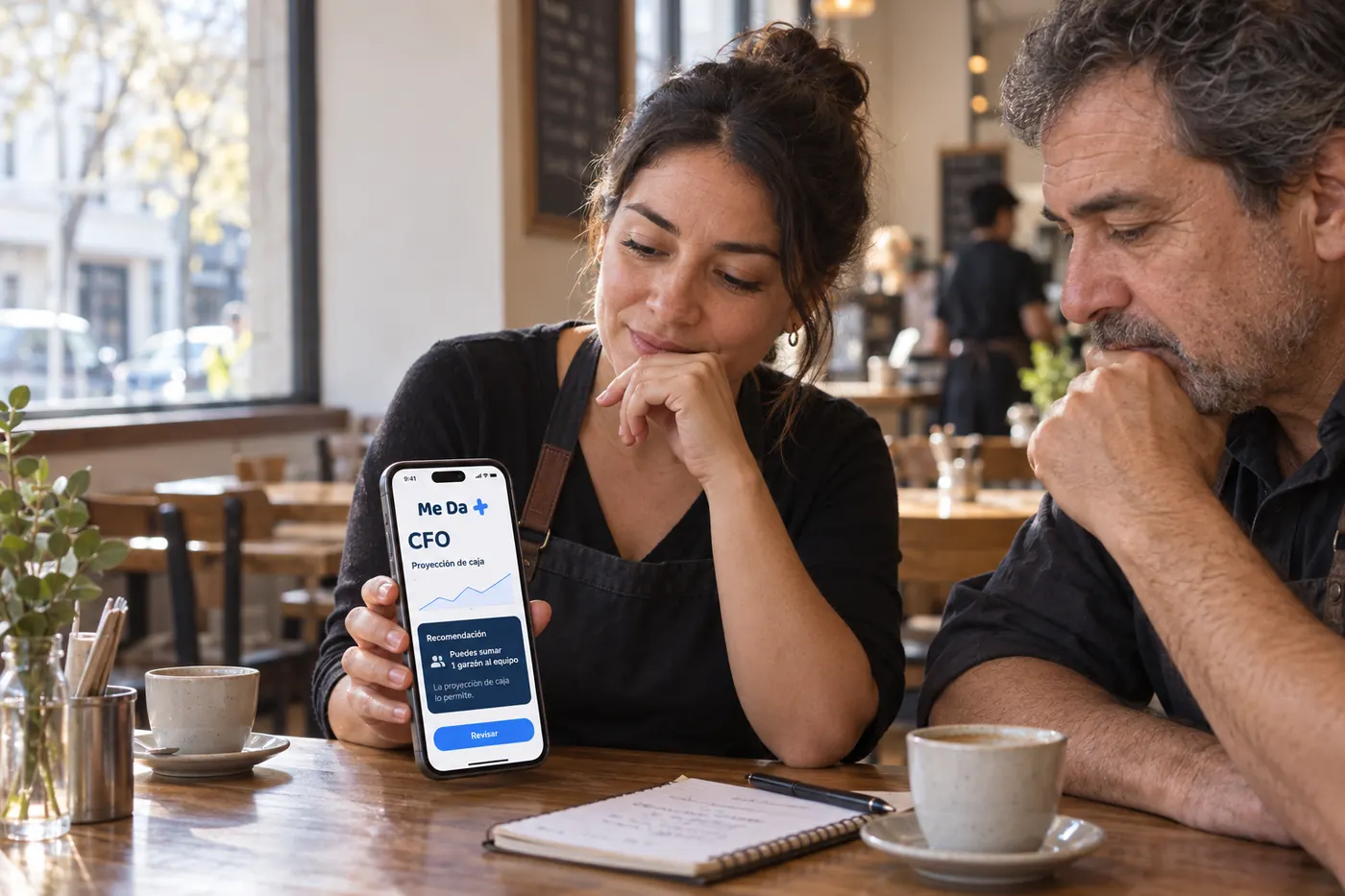 Dos socios de un café leen la recomendación del CFO con superinteligencia en el teléfono antes de decidir.