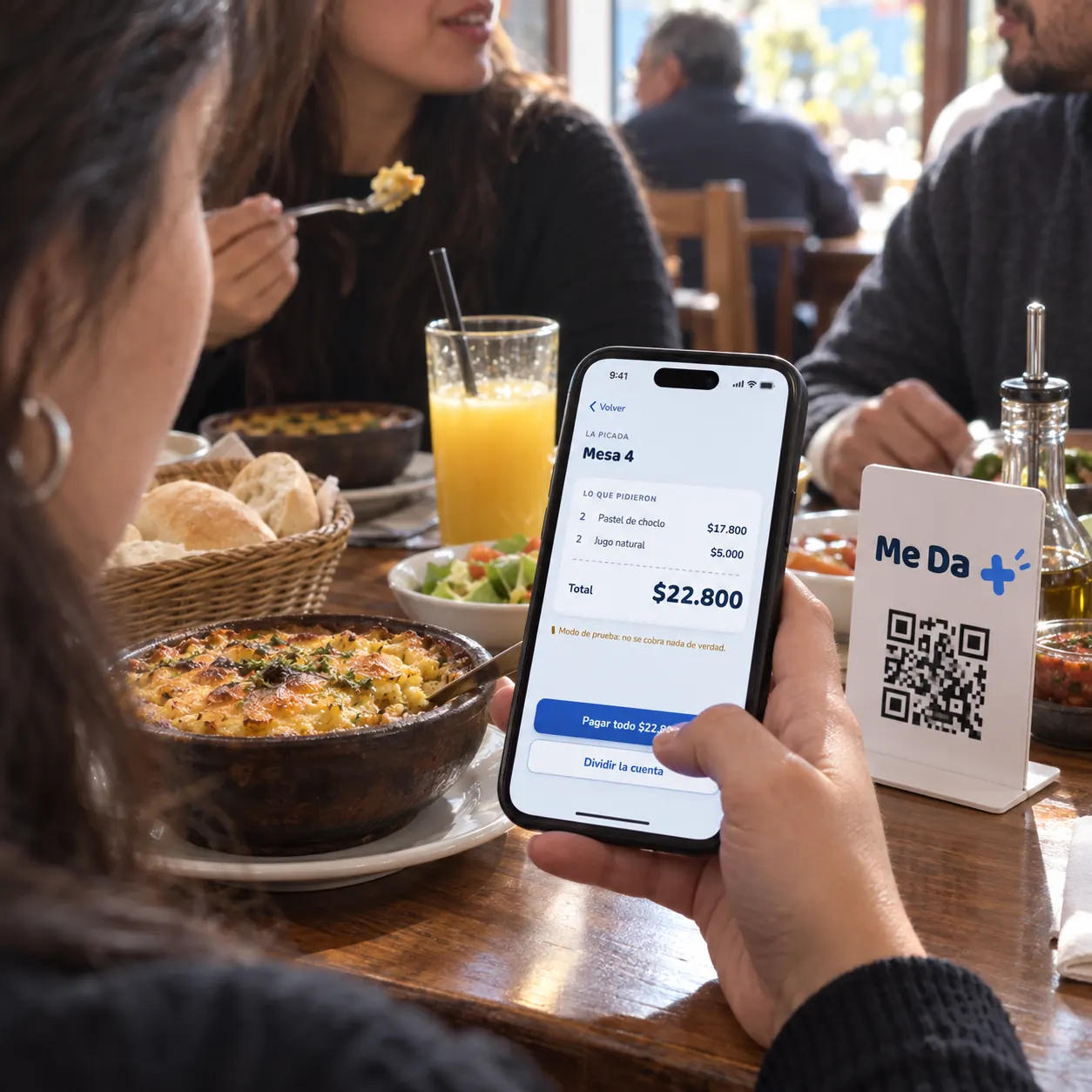 Clienta paga la cuenta de la mesa desde su teléfono, junto al QR de Me Da +.